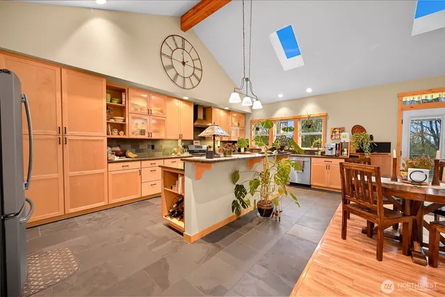 a kitchen with stainless steel appliances a stove a refrigerator cabinets and a dining table