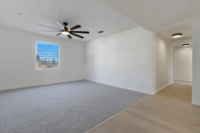 an empty room with a window and a fan