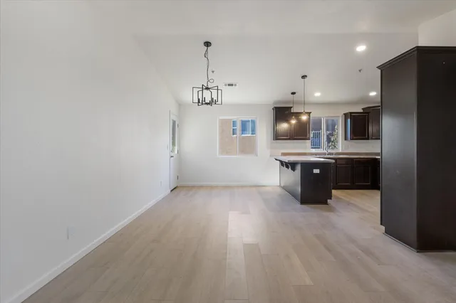 a large kitchen with stainless steel appliances granite countertop a refrigerator a sink dishwasher a stove and a refrigerator with wooden floor