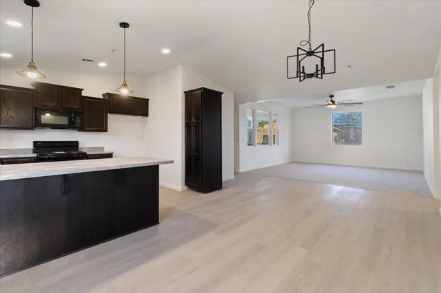 a kitchen with stainless steel appliances granite countertop a refrigerator a sink a stove and a refrigerator