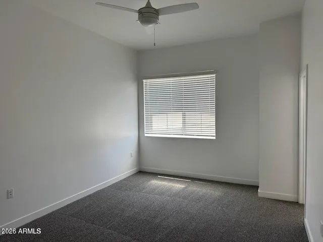 an empty room with a ceiling fan and window