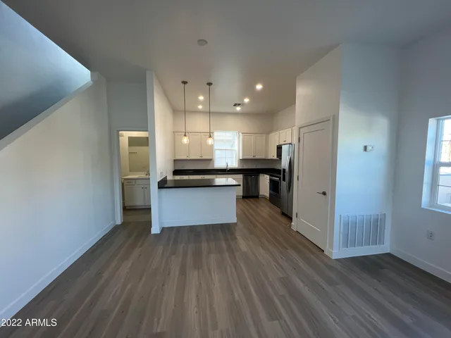 a large kitchen with a center island wooden floor stainless steel appliances and a window