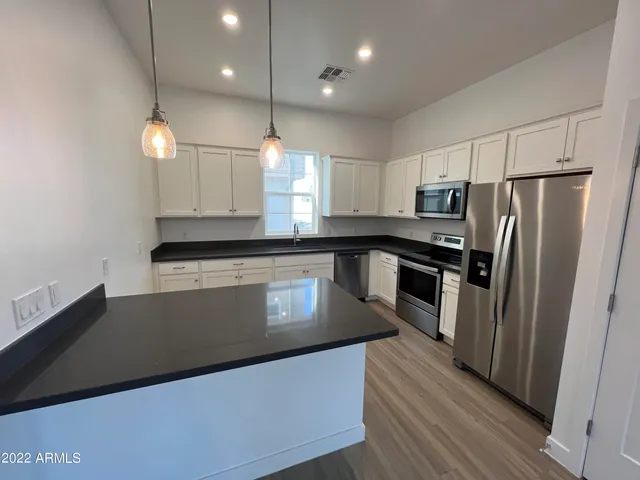 a kitchen with stainless steel appliances granite countertop a refrigerator a stove a sink and a microwave