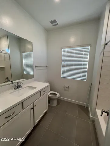 a bathroom with a granite countertop sink a toilet and a mirror