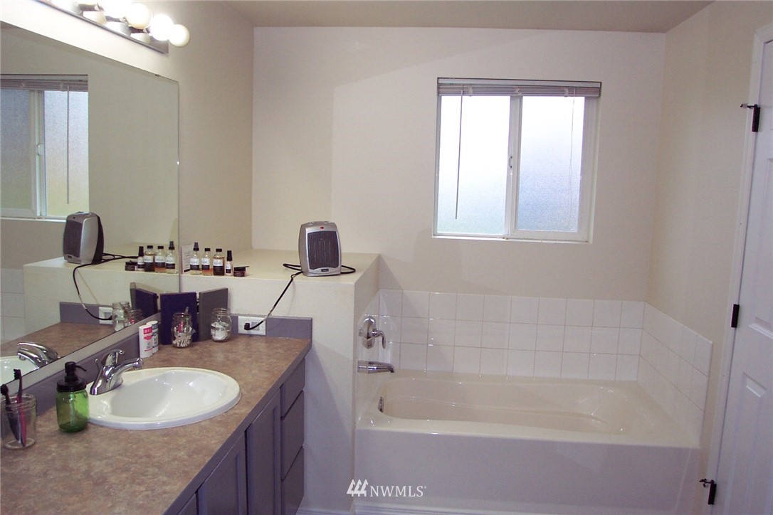 9222 176th Avenue Southwest Rochester, WA 98579 - Photo 12 of 21 a bathroom with a granite countertop sink a mirror a bathtub and next to a window