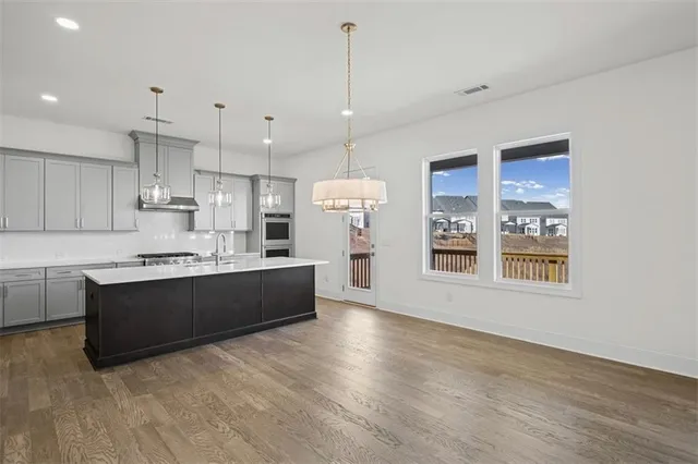 a large kitchen with kitchen island a large counter top space a sink stainless steel appliances and cabinets