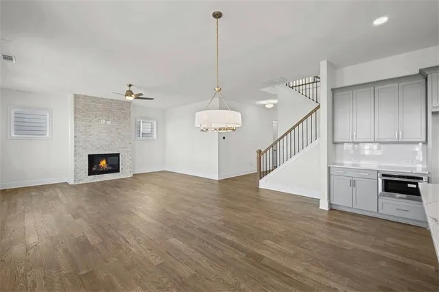 a view of an empty room with wooden floor fireplace and a window