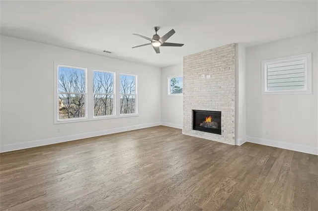 a view of an empty room with wooden floor fireplace and a window
