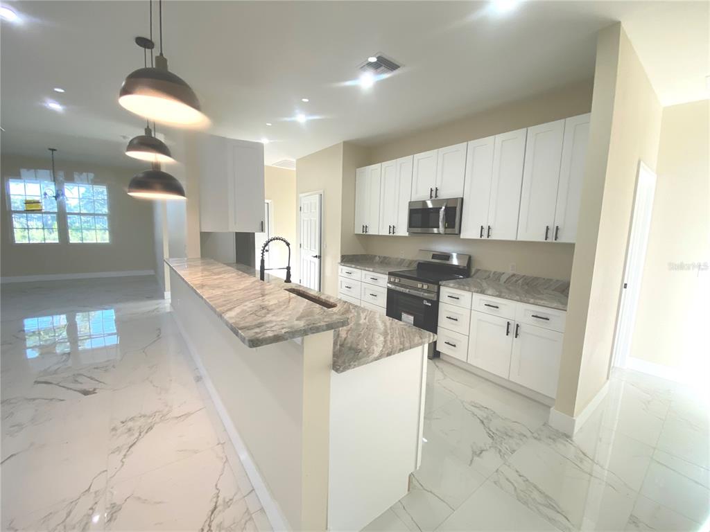 4449 Schumacher Road Sebring, FL 33872 - Photo 12 of 32 a kitchen with stainless steel appliances granite countertop a stove a sink and a refrigerator