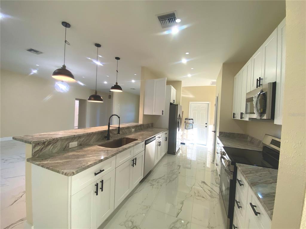 4449 Schumacher Road Sebring, FL 33872 - Photo 13 of 32 a large kitchen with kitchen island a sink stove and refrigerator