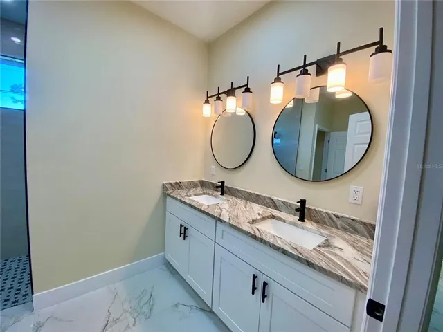 a bathroom with a granite countertop double vanity sink and a mirror