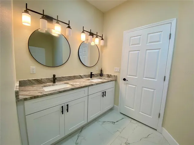 a bathroom with a granite countertop double vanity sink and a mirror