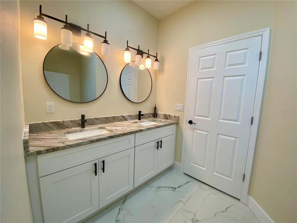 4449 Schumacher Road Sebring, FL 33872 - Photo 17 of 32 a bathroom with a granite countertop double vanity sink and a mirror
