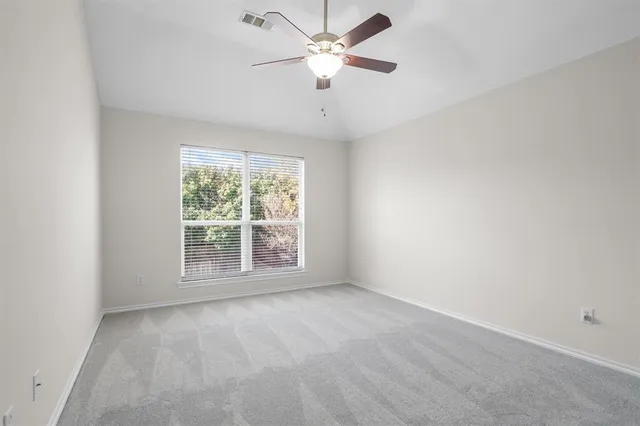 an empty room with a window and a fan