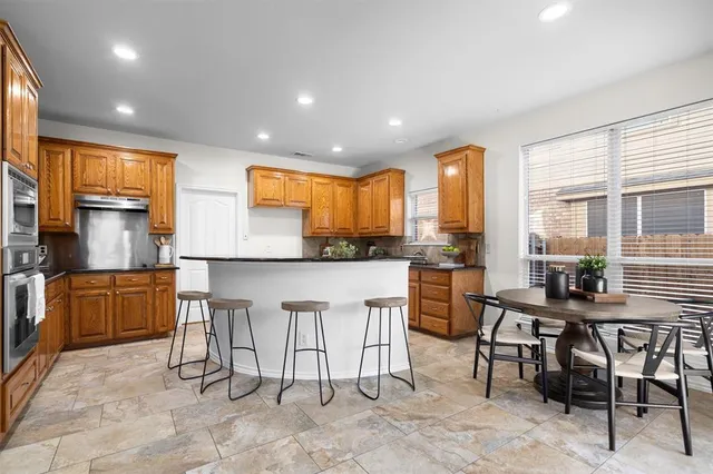a kitchen with stainless steel appliances kitchen island granite countertop a table and chairs in it