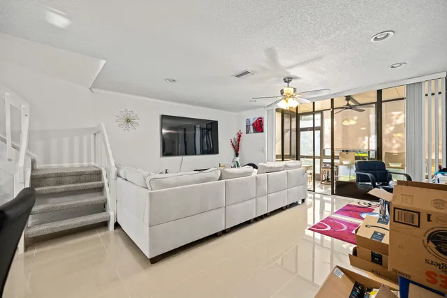 a living room with furniture a flat screen tv and a floor to ceiling window