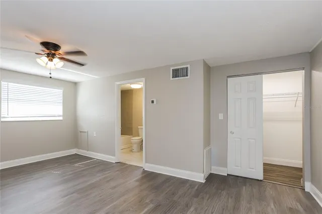 a view of empty room with wooden floor and fan
