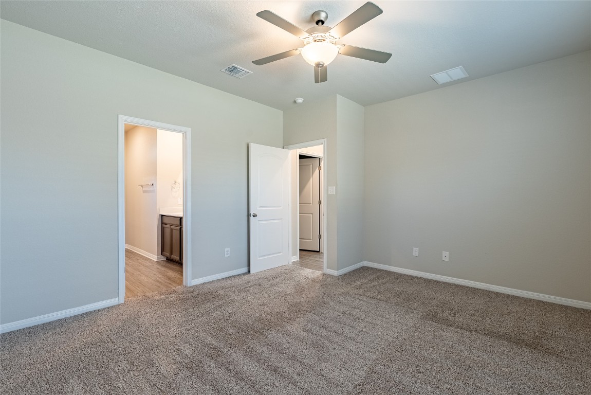 107 Cona Way Hutto, TX 78634 - Photo 12 of 26 Unfurnished bedroom featuring light carpet, a ceiling fan, and ensuite bathroom