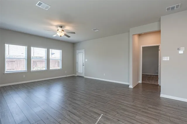 an empty room with wooden floor and windows