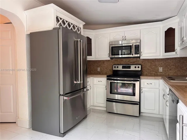 a kitchen with stainless steel appliances and refrigerator