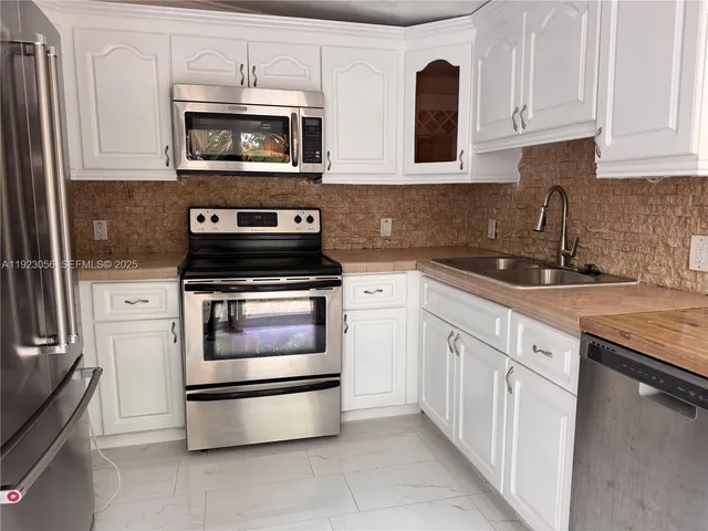a kitchen with granite countertop white cabinets and stainless steel appliances