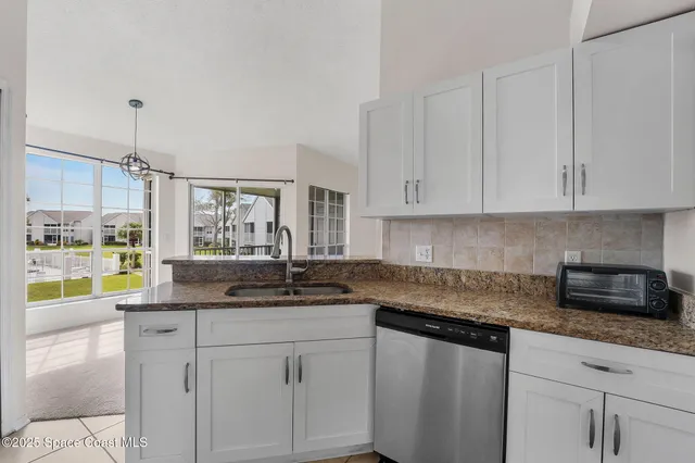 a kitchen with stainless steel appliances granite countertop a sink and a white cabinets