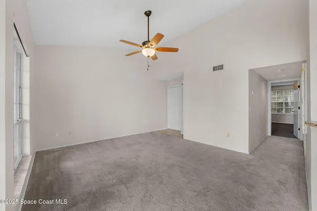 a view of a room with a ceiling fan and window