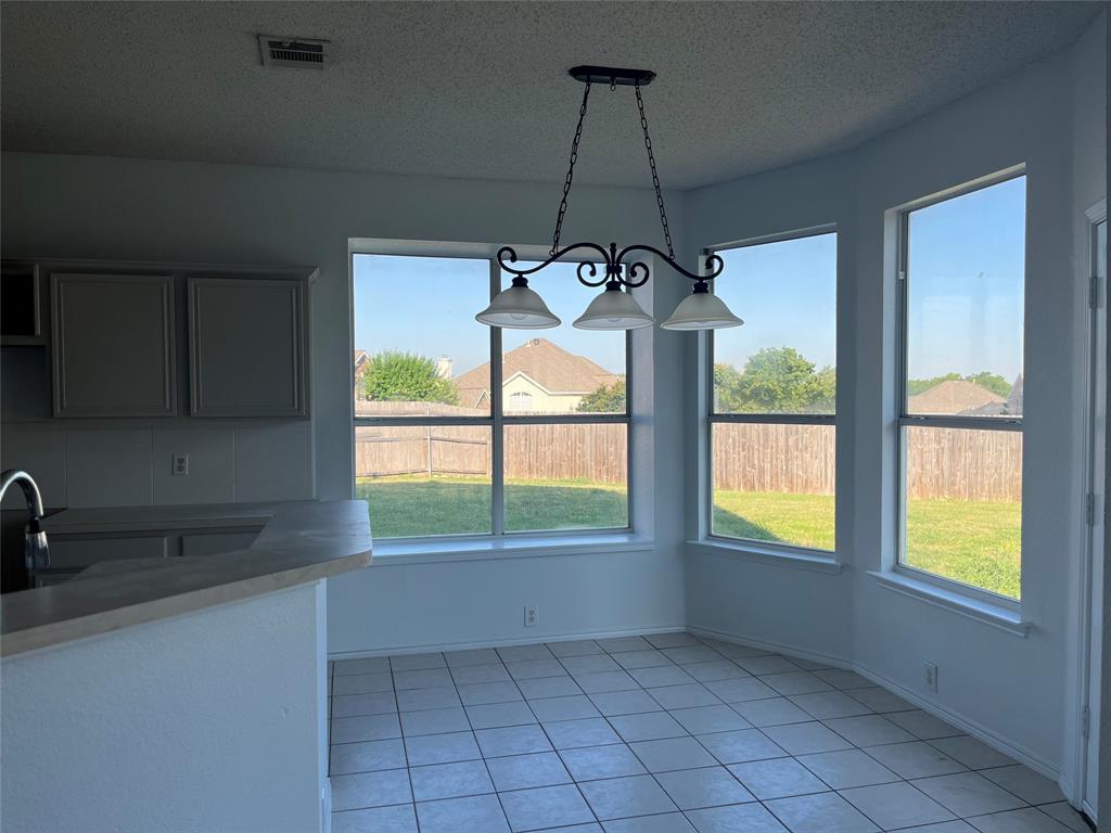 7929 Park Ridge Drive Fort Worth, TX 76137 - Photo 7 of 13 Breakfast nook with bay windows, ceramic tile flooring, and a wrought iron chandelier