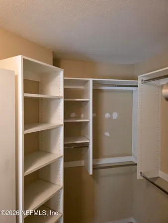 an empty room with a chandelier fan and closet