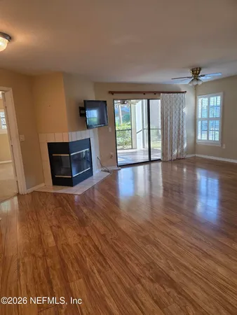 a view of an empty room with glass door and wooden floor