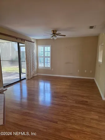 a view of empty room with wooden floor and fan