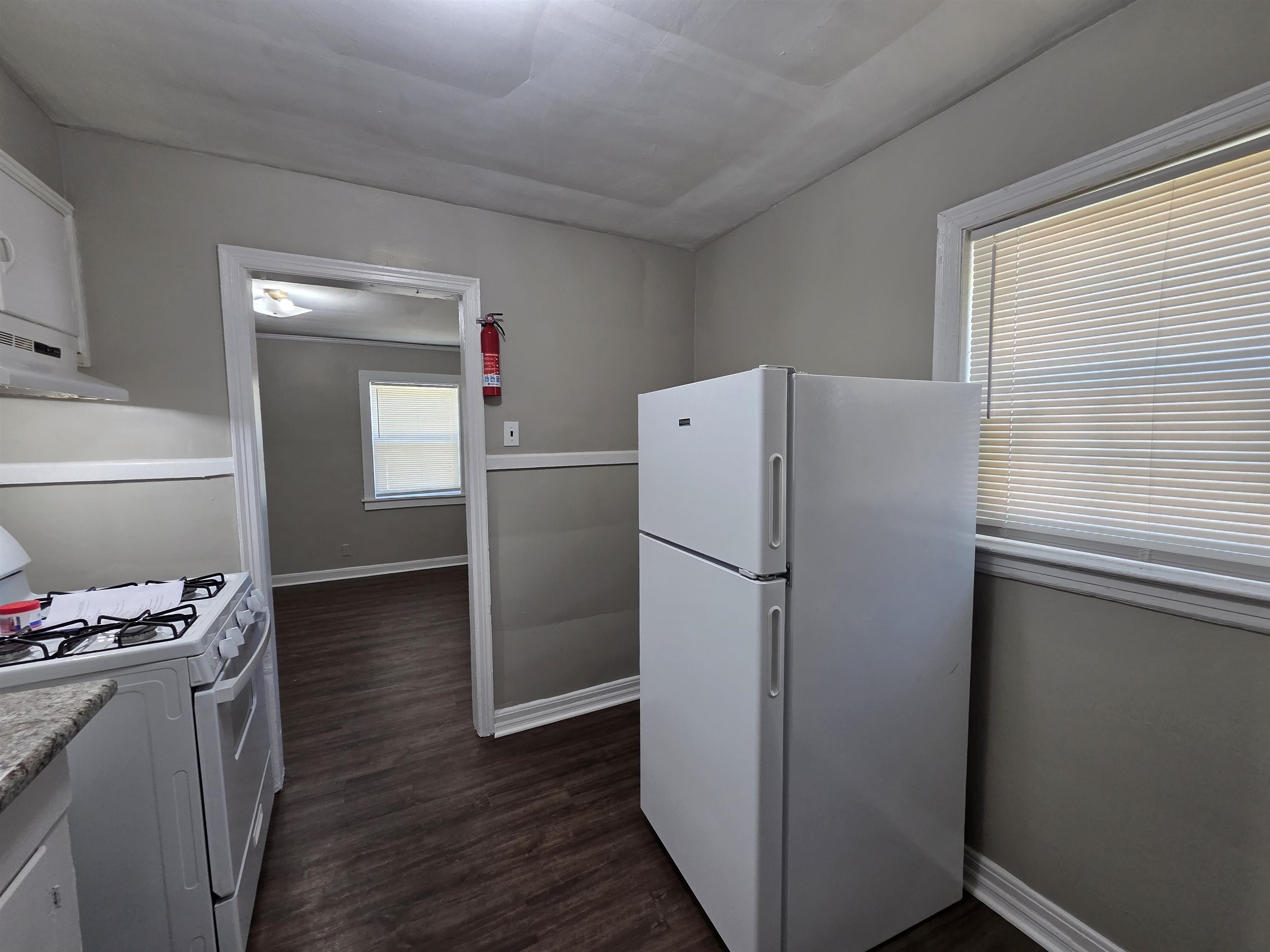 802 North Dunlap Street Memphis, TN 38107 - Photo 11 of 18 Kitchen featuring white appliances, white cabinetry, dark wood-type flooring, extractor fan, and light countertops