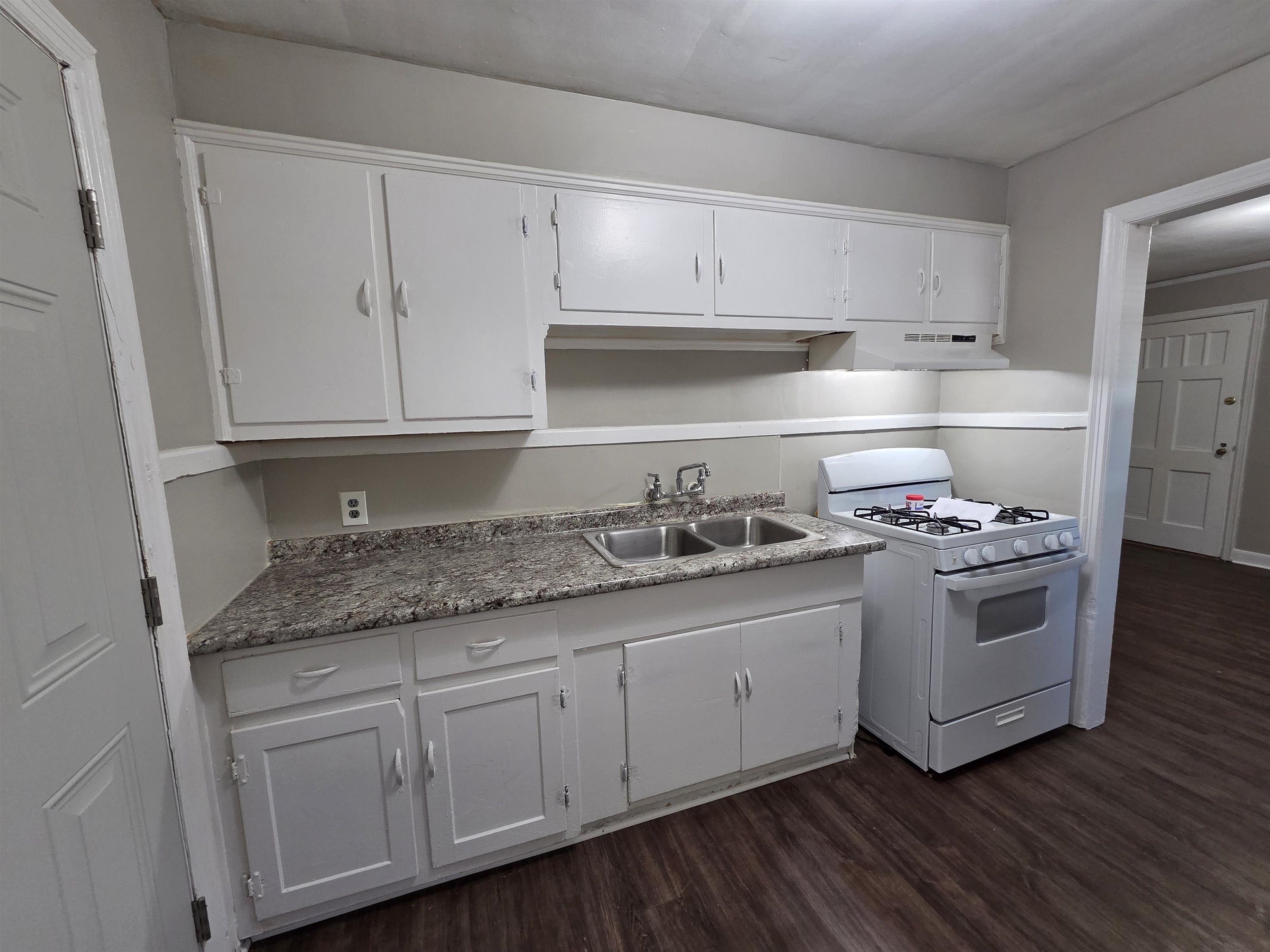 802 North Dunlap Street Memphis, TN 38107 - Photo 10 of 18 Kitchen featuring white range with gas stovetop, dark wood-type flooring, white cabinetry, light countertops, and under cabinet range hood