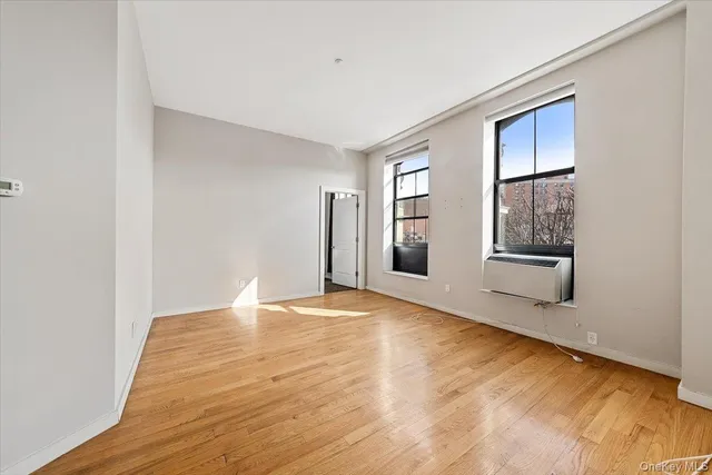 a view of an empty room with window and wooden floor