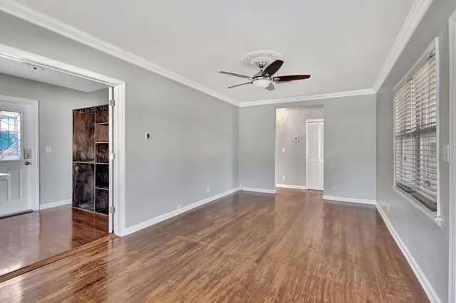 a view of an empty room with wooden floor and a window