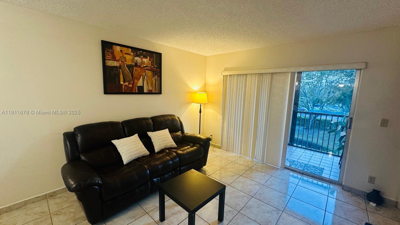 2230 North Cypress Bend Drive, Unit 309 Pompano Beach, FL 33069 - Photo 8 of 31 a living room with furniture and a floor to ceiling window
