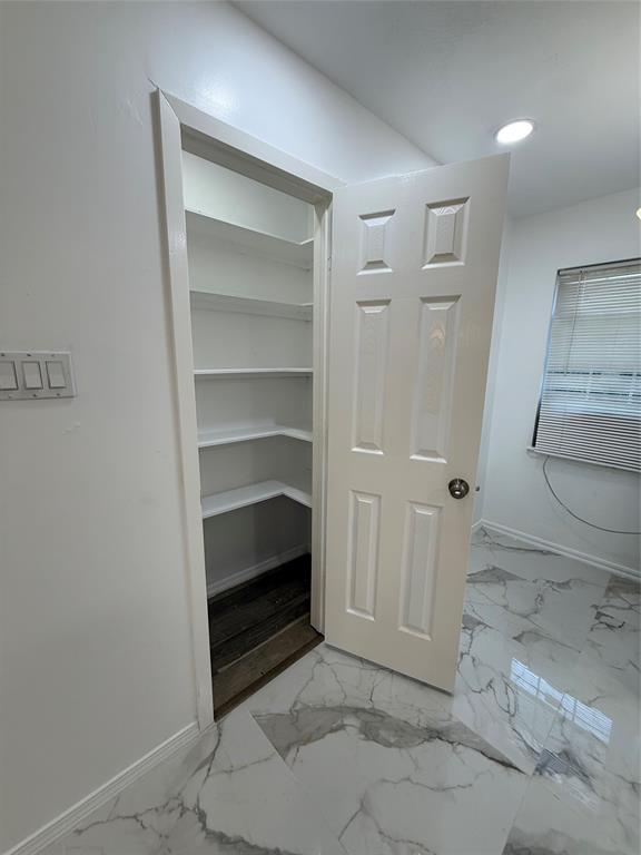 2529 Rutgers Drive Irving, TX 75062 - Photo 12 of 38 Corner pantry featuring built-in shelving, a paneled door, and a contrasting wood-finish threshold