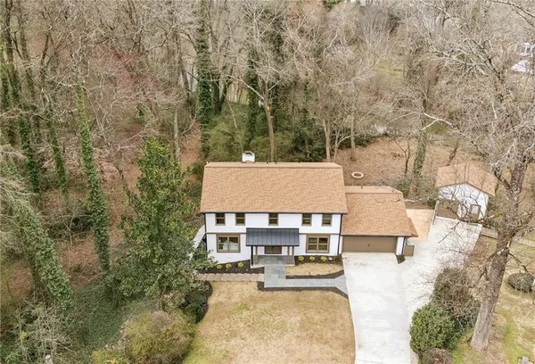 an aerial view of a house with swimming pool and large trees