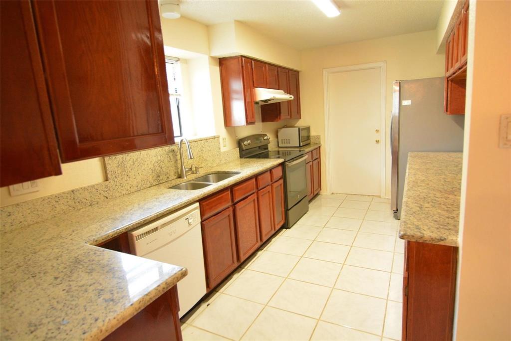 210 Apollo Road Garland, TX 75040 - Photo 2 of 23 Kitchen featuring extensive wood cabinetry, light speckled countertops, stainless steel appliances, a double basin sink, and tile flooring
