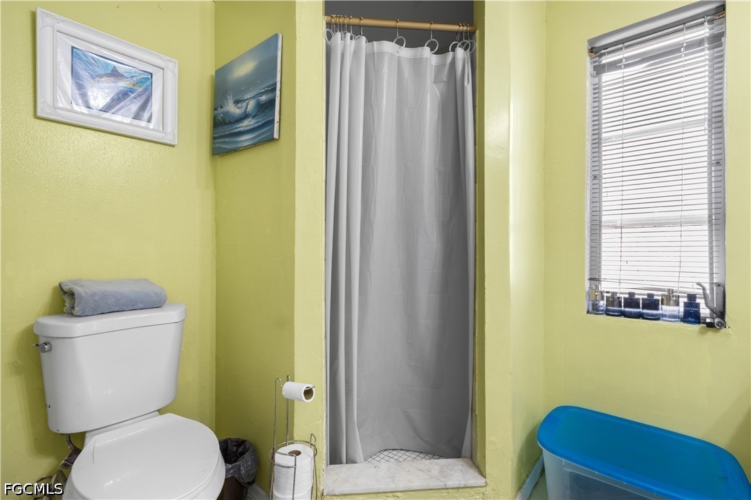 18 Illinois Road Lehigh Acres, FL 33936 - Photo 22 of 45 a bathroom with a toilet and a shower curtain