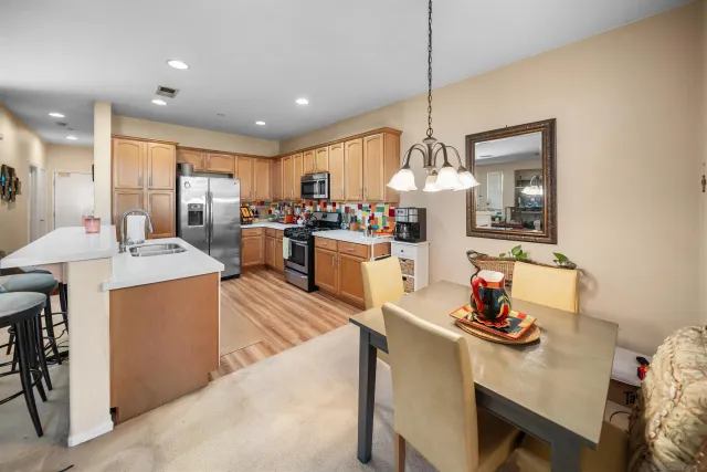 a kitchen with stainless steel appliances granite countertop a sink dishwasher and a dining table with chairs