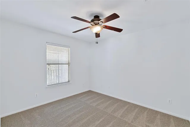 an empty room with window and ceiling fan