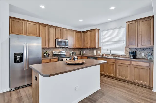 a kitchen with stainless steel appliances granite countertop a refrigerator a stove a sink and a microwave