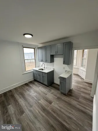 a living room with stainless steel appliances kitchen island granite countertop a sink and a large window