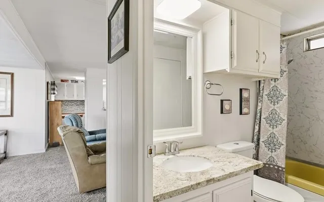 a bathroom with a granite countertop sink toilet and shower