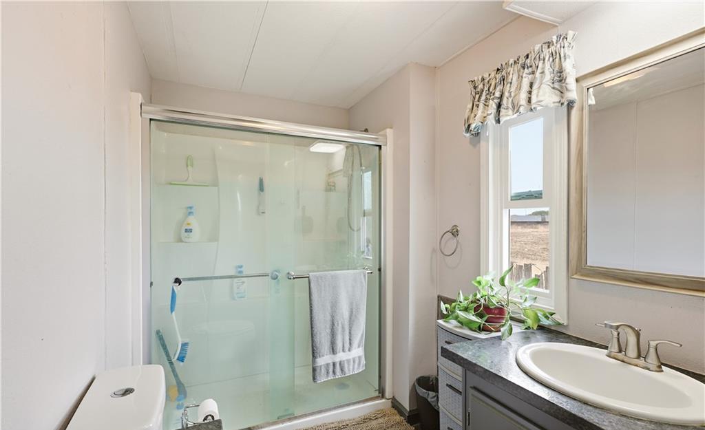 2240 Golden Oak Lane Merced, CA 95340 - Photo 28 of 44 a bathroom with a granite countertop sink a mirror a vanity and a shower