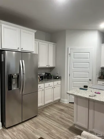 a kitchen with stainless steel appliances granite countertop a refrigerator sink and white cabinets