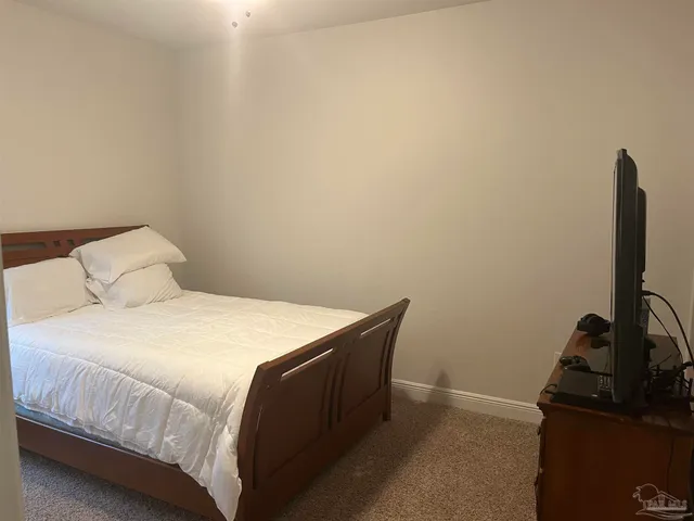 a bedroom with a bed and a flat tv screen on a dresser