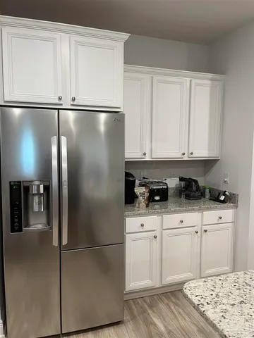 a kitchen with stainless steel appliances granite countertop a refrigerator a stove and white cabinets