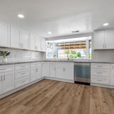 a kitchen with granite countertop white cabinets white stainless steel appliances and sink